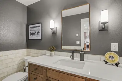 Stylish modern half bath with warm wood vanity and elegant lighting