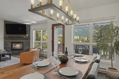 Mountain-view dining and cozy fireplace living space with balcony access
