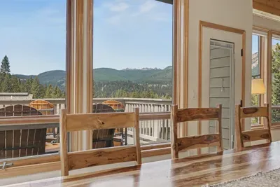 Sunny dining space with mountain-view windows and scenic outdoor deck