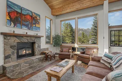 Cozy mountain living room with stone fireplace and scenic views