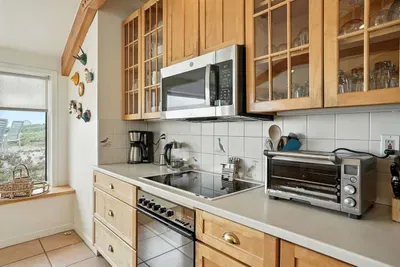 - Bright kitchen with wood cabinetry, large windows & modern appliances for easy cooking  - Features electric cooktop, microwave, toaster oven & coffee maker for convenience  - Scenic dune views create a relaxing atmosphere while you prepare meals