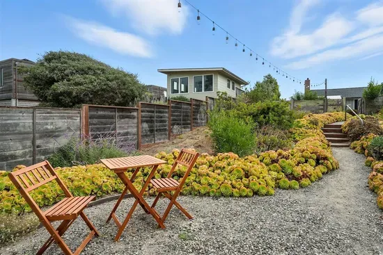- Charming garden seating area with bistro table and string lights overhead  - Surrounded by beautiful greenery and colorful plants for a peaceful setting  - Perfect spot for morning coffee, reading, or intimate evening chats