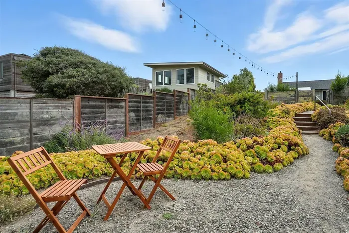 - Charming garden seating area with bistro table and string lights overhead  - Surrounded by beautiful greenery and colorful plants for a peaceful setting  - Perfect spot for morning coffee, reading, or intimate evening chats