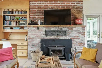 - Cozy living space with brick fireplace, mounted TV, and built in bookshelves  - Comfortable seating and warm accents make it perfect for relaxation  - Ideal for unwinding with a good book or movie after a day by the coast
