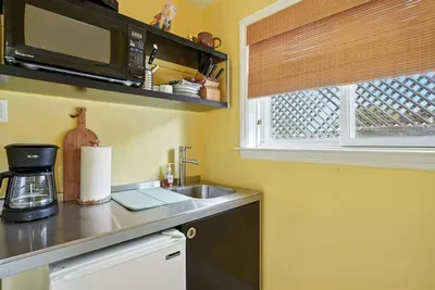 - Compact kitchenette with stainless steel sink, mini fridge, and microwave  - Open shelving stocked with dishes, mugs, and cooking essentials for convenience  - Ideal for preparing light meals or morning coffee before heading out