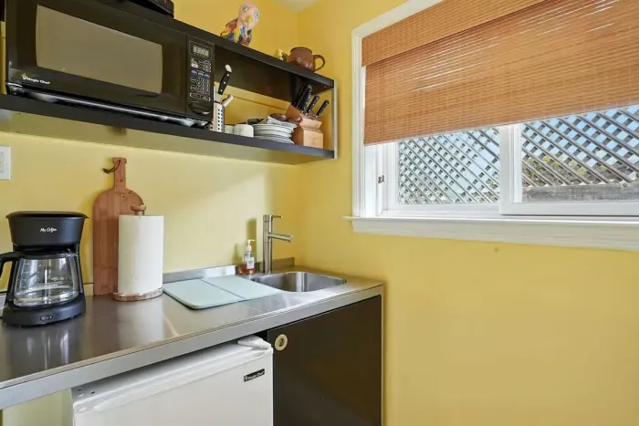 - Compact kitchenette with stainless steel sink, mini fridge, and microwave  - Open shelving stocked with dishes, mugs, and cooking essentials for convenience  - Ideal for preparing light meals or morning coffee before heading out