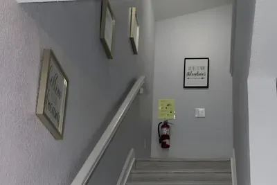 - Stairway with soft gray walls and motivational art for an inviting ascent  
- Wide steps and railing provide safety and ease for all guests  
- Leads to cozy upstairs bedrooms and additional living spaces
