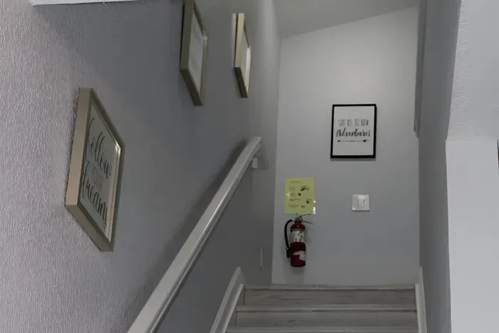 - Stairway with soft gray walls and motivational art for an inviting ascent  
- Wide steps and railing provide safety and ease for all guests  
- Leads to cozy upstairs bedrooms and additional living spaces