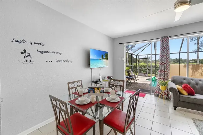 - Dining area with glass top table set for four beside sliding doors to the pool  
- Wall art and patterned curtains add playful style to the bright interior  
- Enjoy meals indoors with views of the screened in patio and sparkling pool