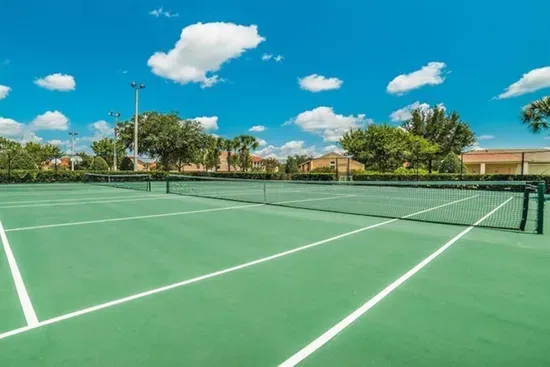 Outdoor tennis court under a bright blue sky.