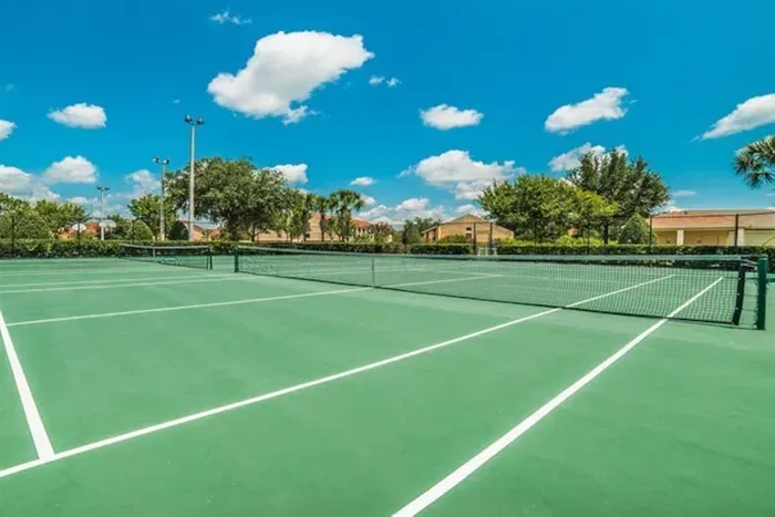 Outdoor tennis court under a bright blue sky.