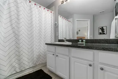 - Sleek bathroom with white cabinetry, granite countertop, and large mirror  
- Chevron pattern shower curtain adds a modern touch to the clean design  
- Functional layout ideal for refreshing after a day of adventures