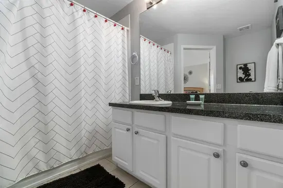 - Sleek bathroom with white cabinetry, granite countertop, and large mirror  
- Chevron pattern shower curtain adds a modern touch to the clean design  
- Functional layout ideal for refreshing after a day of adventures