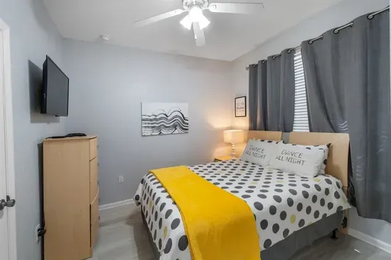 - Cozy bedroom with queen bed, modern polka dot bedding, and yellow throw  
- Soft lighting and ceiling fan create a comfortable and restful environment  
- Perfect for couples or solo travelers seeking a relaxing night’s sleep