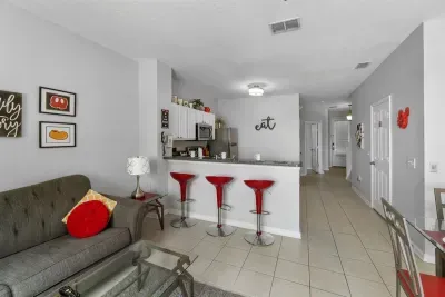 - Cozy living space with soft seating, glass coffee table, and bright accents  
- Kitchen features stainless steel appliances and plenty of counter space  
- Red bar stools add a fun pop of color for casual meals or conversation