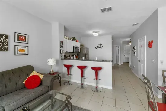 - Cozy living space with soft seating, glass coffee table, and bright accents  
- Kitchen features stainless steel appliances and plenty of counter space  
- Red bar stools add a fun pop of color for casual meals or conversation