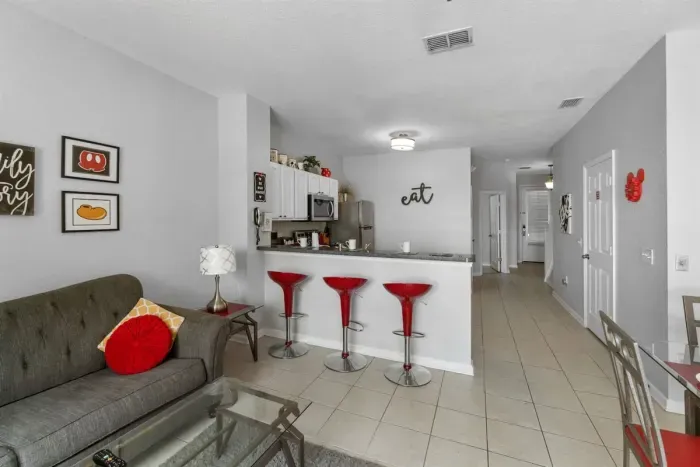- Cozy living space with soft seating, glass coffee table, and bright accents  
- Kitchen features stainless steel appliances and plenty of counter space  
- Red bar stools add a fun pop of color for casual meals or conversation