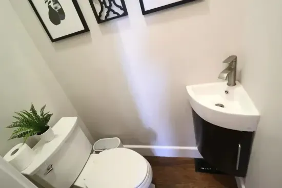 : A stylish and clean half-bath, featuring a modern corner vanity to maximize space.