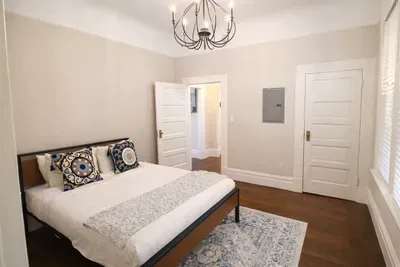 A cozy bedroom setup featuring decorative pillows, a soft area rug, and plenty of space to unwind.