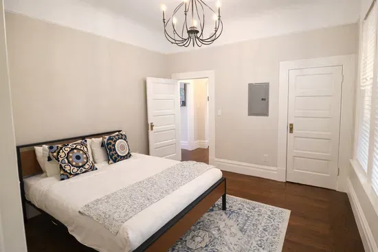 A cozy bedroom setup featuring decorative pillows, a soft area rug, and plenty of space to unwind.
