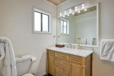 - Bathroom includes single sink vanity with wood cabinetry for storage  
- Wide mirror and bright lights make getting ready a comfortable routine  
- Window offers both natural light and ventilation throughout the day