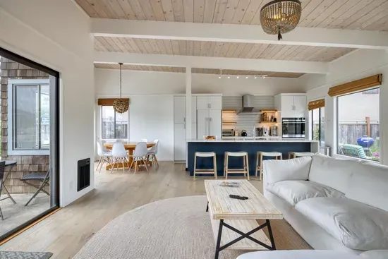 - Open concept living space connects kitchen, dining, and lounging areas  
- Modern kitchen with bar seating and full amenities for home cooking  
- Bright and airy design with large windows showcasing water views