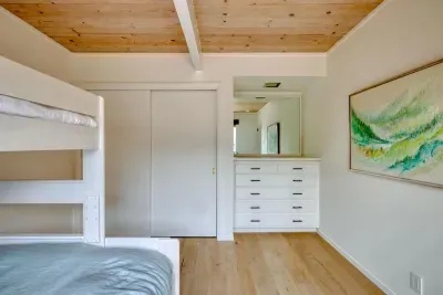 - Spacious bunk room with built in dresser and plenty of closet storage  
- Light wood flooring and minimal decor for a clean, uncluttered vibe  
- Large mirror reflects light, making the room feel open and airy