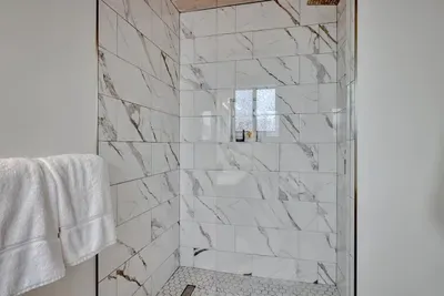 - Modern walk in shower with marble style tile walls for a sleek appearance  
- Built in niche keeps toiletries organized and easily within reach  
- Glass door enclosure creates an open feel while letting light flow freely