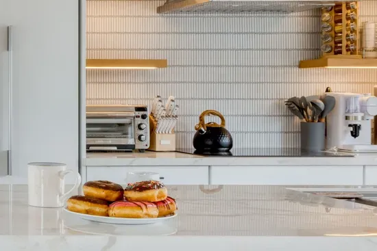 - Kitchen countertop with marble surface and pastries ready to enjoy  
- Open shelving with modern appliances including coffee maker and toaster  
- Warm lighting creates an inviting atmosphere for casual breakfasts