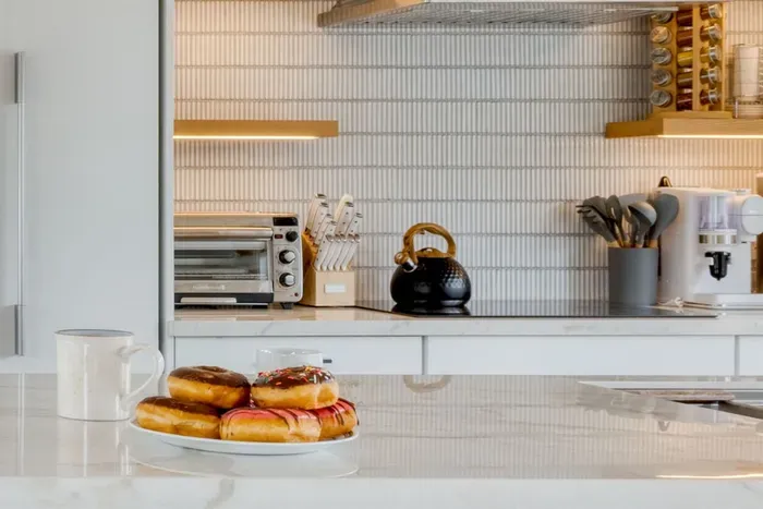 - Kitchen countertop with marble surface and pastries ready to enjoy  
- Open shelving with modern appliances including coffee maker and toaster  
- Warm lighting creates an inviting atmosphere for casual breakfasts
