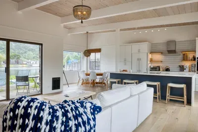 - Cozy living area with white sectional seating and bright open concept  
- Sliding glass doors lead to the patio for indoor outdoor living  
- Kitchen and dining areas positioned for easy flow and entertaining