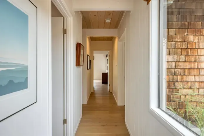 - Hallway with large windows providing views of the home’s exterior  
- Natural wood ceiling and floors create a warm, welcoming pathway  
- Access to bedrooms and living areas conveniently from this corridor