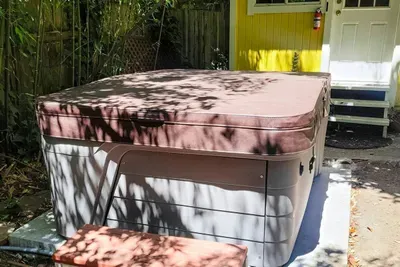- Covered hot tub with secure insulated lid for year round relaxation  
- Located beside the cheerful yellow garden shed for added charm  
- Private setting surrounded by natural shade for peaceful soaking