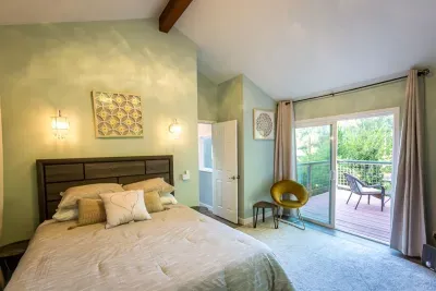 - Elegant bedroom with king bed, vaulted ceiling, and private balcony access  
- Soft green walls pair beautifully with the bright airy atmosphere indoors  
- Perfect place to enjoy morning coffee with fresh air and scenic views