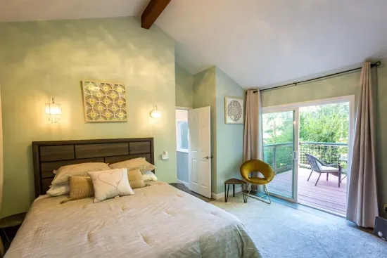 - Elegant bedroom with king bed, vaulted ceiling, and private balcony access  
- Soft green walls pair beautifully with the bright airy atmosphere indoors  
- Perfect place to enjoy morning coffee with fresh air and scenic views