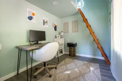 - Dedicated workspace with desk, chair, and monitor for remote work ease  
- Soft green walls and natural light make this office bright and inviting  
- Unique loft ladder adds character and connects to an upper level nook