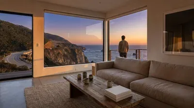 Man watching sunset over ocean from modern living room