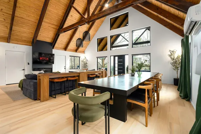 Stunning vaulted great room with fireplace, dining for groups, and forest views