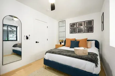 Cozy modern bedroom with plush bedding, chic decor, and full-length mirror