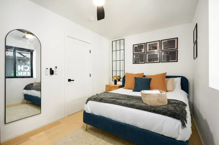Cozy modern bedroom with plush bedding, chic decor, and full-length mirror