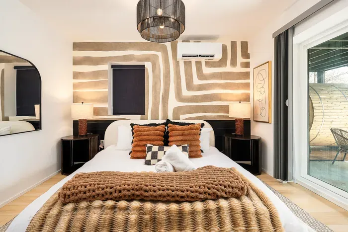 Designer bedroom with bold mural, cozy textures, and private patio access