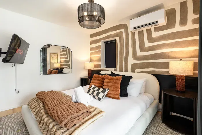 Cozy designer bedroom with plush bedding, TV, and bold accent wall