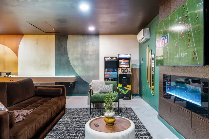 Game room lounge with arcade machines, shuffleboard, fireplace & big TV