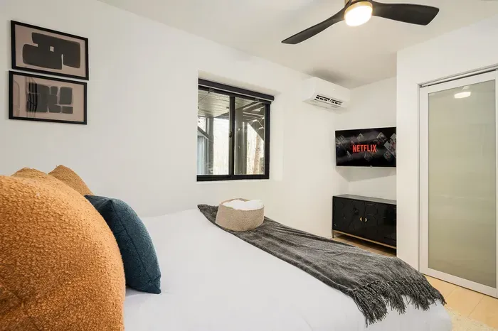 Bright modern bedroom with streaming TV, cozy bed, and minimalist style