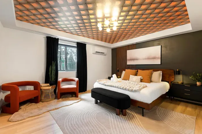 Designer king bedroom with bold ceiling, cozy seating, and modern style