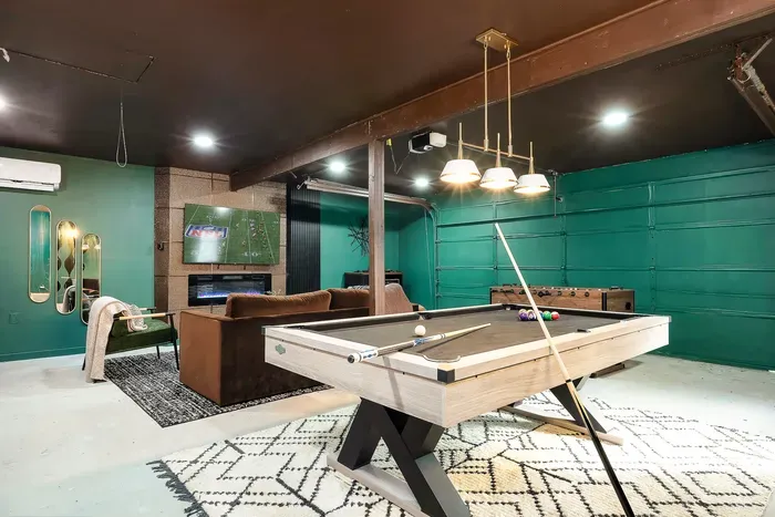 Stylish game room with pool table, foosball, TV, and cozy lounge area
