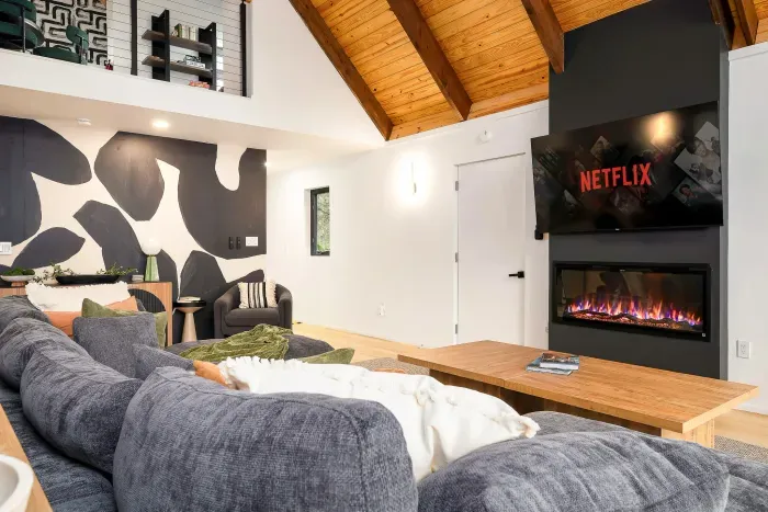 Cozy modern lounge with vaulted wood ceilings, fireplace, and big-screen TV