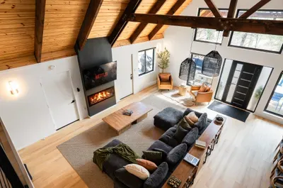 Vaulted great room with fireplace, big windows, and cozy modern seating