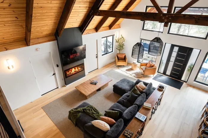 Vaulted great room with fireplace, big windows, and cozy modern seating