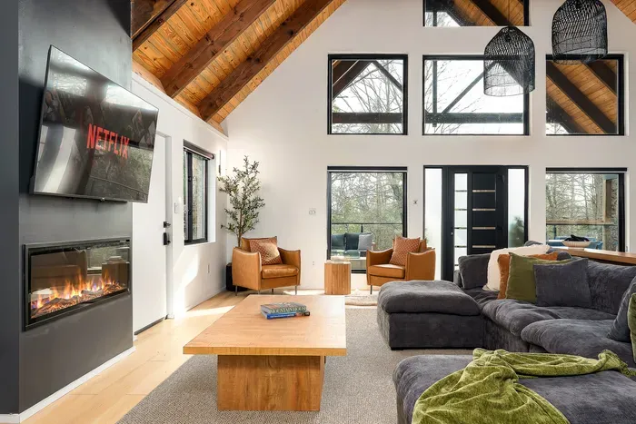 Vaulted-ceiling great room with fireplace, big windows, and cozy sectional